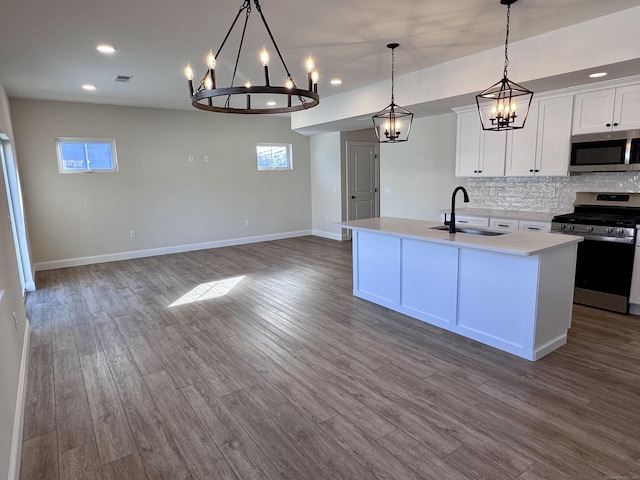 kitchen featuring tasteful backsplash, appliances with stainless steel finishes, wood finished floors, light countertops, and a sink