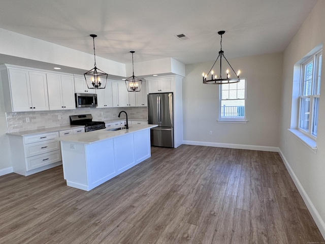 kitchen featuring visible vents, decorative backsplash, appliances with stainless steel finishes, white cabinetry, and a sink