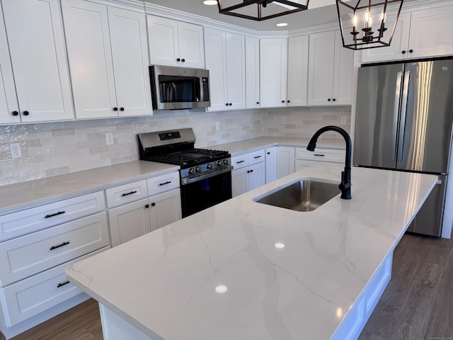 kitchen featuring white cabinets, appliances with stainless steel finishes, dark wood-style flooring, decorative light fixtures, and a sink