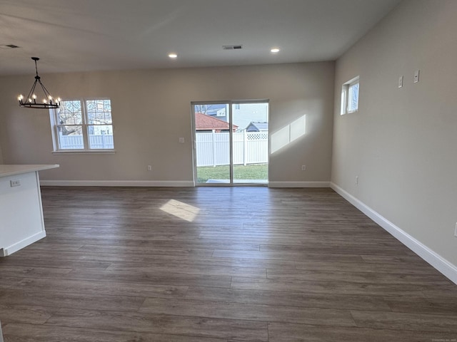 interior space featuring dark wood-style flooring, visible vents, a notable chandelier, and baseboards