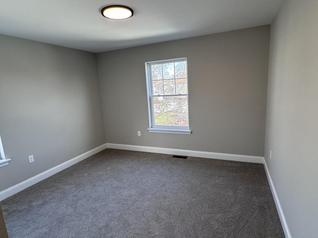 unfurnished room with visible vents, baseboards, and dark colored carpet