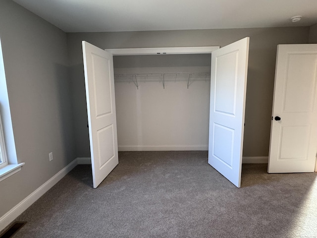 unfurnished bedroom with a closet, carpet, visible vents, and baseboards