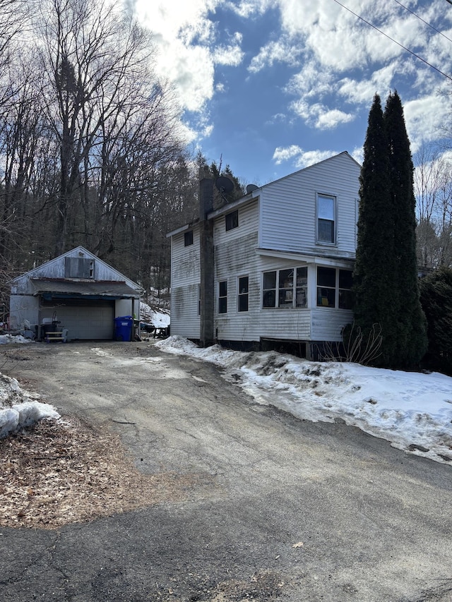 view of front of house featuring a garage, a chimney, and an outdoor structure