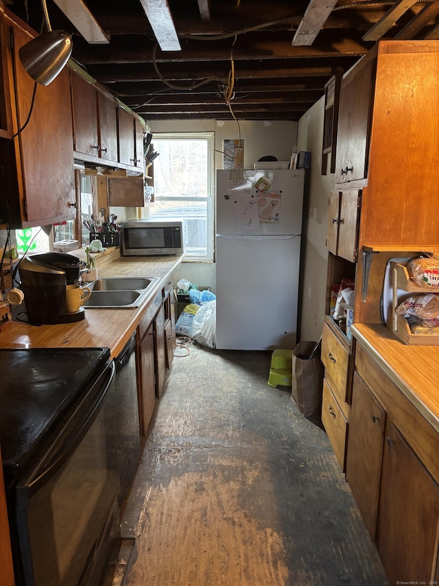 kitchen with black range with electric cooktop, a sink, light countertops, freestanding refrigerator, and stainless steel microwave