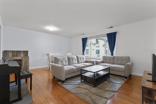 living room with visible vents, hardwood / wood-style flooring, and baseboards