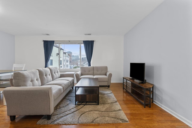 living room featuring baseboards, visible vents, and wood finished floors