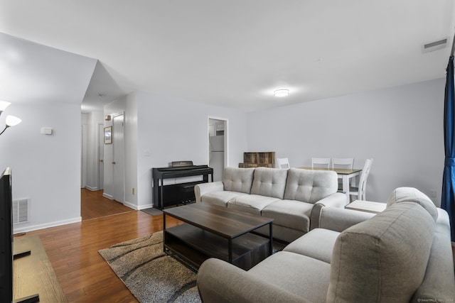 living area with baseboards, visible vents, and wood finished floors