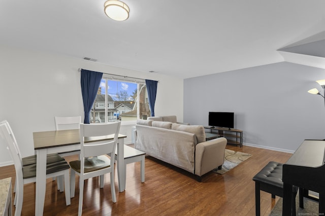 living room featuring lofted ceiling, baseboards, visible vents, and wood finished floors