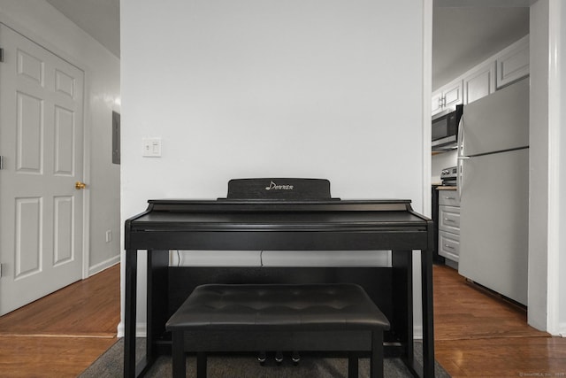 details with freestanding refrigerator, stainless steel microwave, baseboards, and wood finished floors