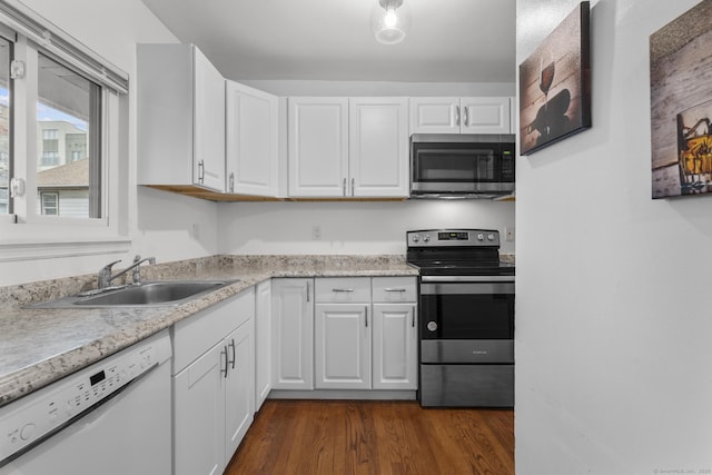 kitchen featuring stainless steel appliances, a sink, white cabinets, light countertops, and dark wood-style floors