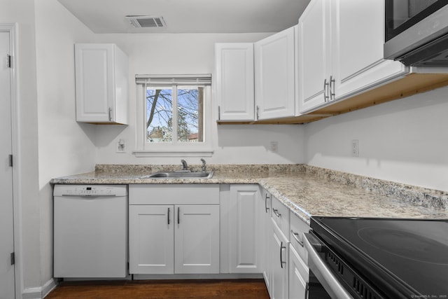 kitchen with a sink, visible vents, white cabinetry, appliances with stainless steel finishes, and dark wood finished floors