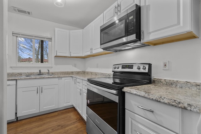 kitchen featuring visible vents, appliances with stainless steel finishes, wood finished floors, white cabinetry, and a sink