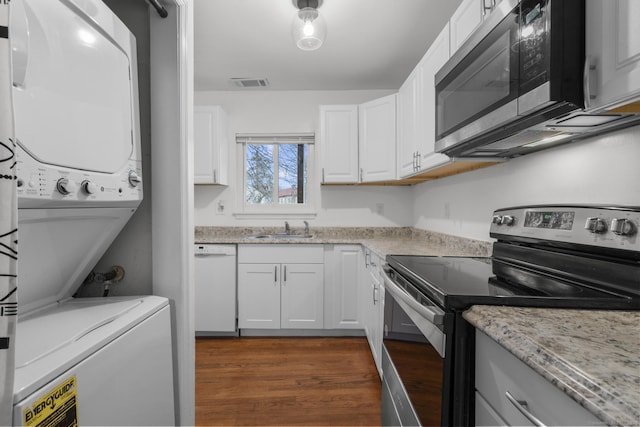 kitchen with stacked washer and dryer, visible vents, stainless steel appliances, white cabinetry, and a sink