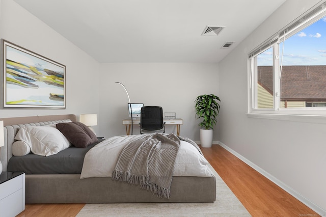 bedroom featuring light wood-style flooring, visible vents, and baseboards