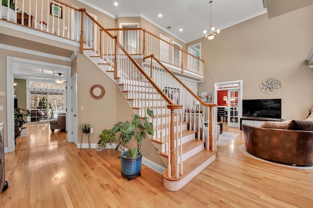 stairs with baseboards, crown molding, a towering ceiling, and hardwood / wood-style floors