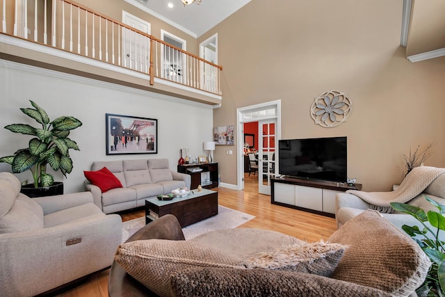 living room featuring ornamental molding, a towering ceiling, baseboards, and wood finished floors