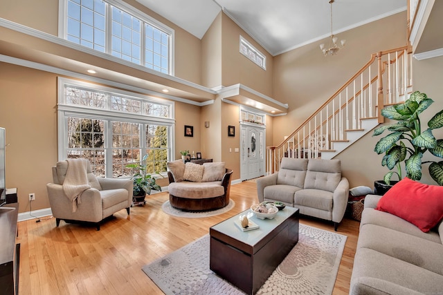 living room featuring baseboards, hardwood / wood-style flooring, an inviting chandelier, stairs, and crown molding