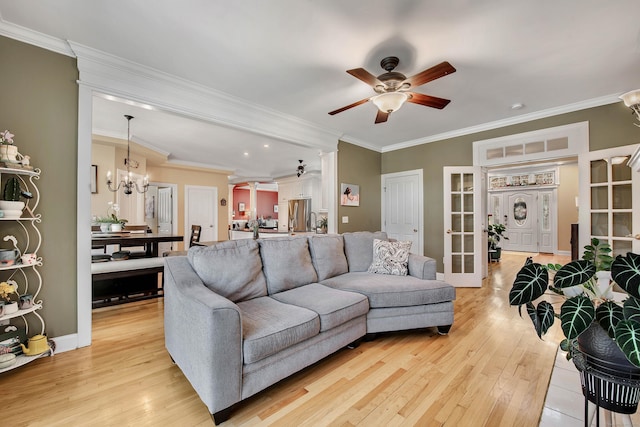 living room featuring ceiling fan with notable chandelier, french doors, light wood finished floors, and ornamental molding