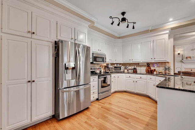 kitchen featuring white cabinets, light wood-style flooring, stainless steel appliances, crown molding, and a sink