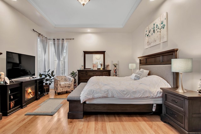 bedroom featuring a tray ceiling and light wood-style flooring