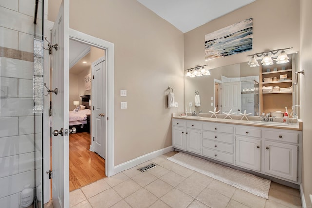 ensuite bathroom featuring double vanity, tile patterned flooring, a sink, and visible vents