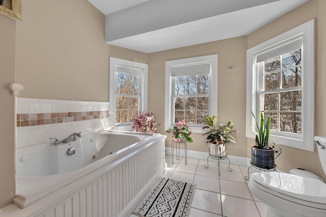 full bathroom with baseboards, toilet, a tub with jets, and tile patterned floors