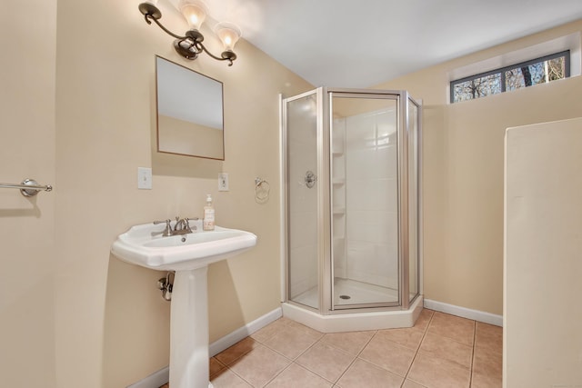 full bath with a stall shower, tile patterned flooring, baseboards, and a sink