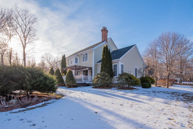 view of snowy exterior with a chimney and a pergola