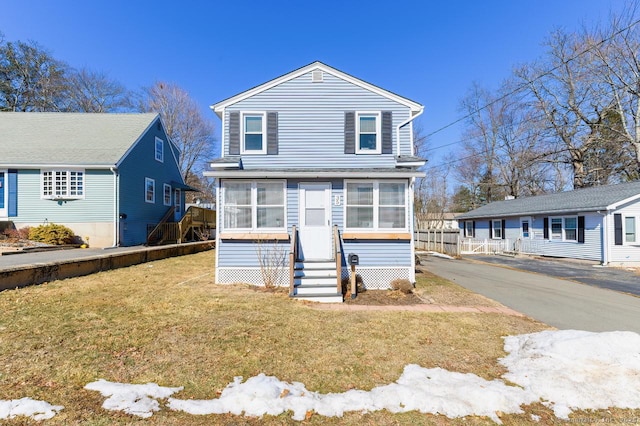 view of front of home with entry steps, driveway, and a front lawn