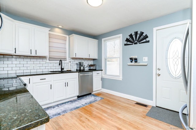 kitchen with a sink, visible vents, white cabinetry, appliances with stainless steel finishes, and light wood finished floors