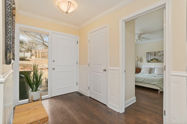 foyer featuring a ceiling fan, ornamental molding, and dark wood-type flooring