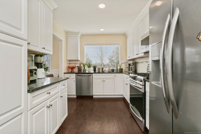 kitchen with appliances with stainless steel finishes, dark wood-style flooring, a sink, and white cabinets