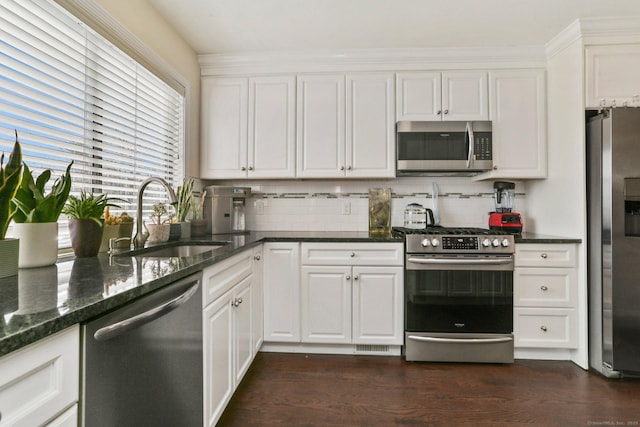 kitchen featuring appliances with stainless steel finishes, a sink, white cabinetry, and tasteful backsplash