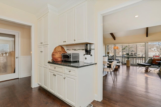 kitchen with dark wood-style floors, beam ceiling, white cabinets, and backsplash