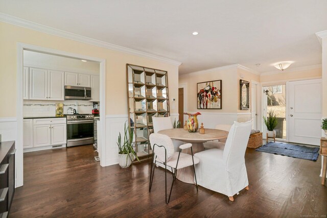 dining space featuring a wainscoted wall, dark wood finished floors, crown molding, and a decorative wall