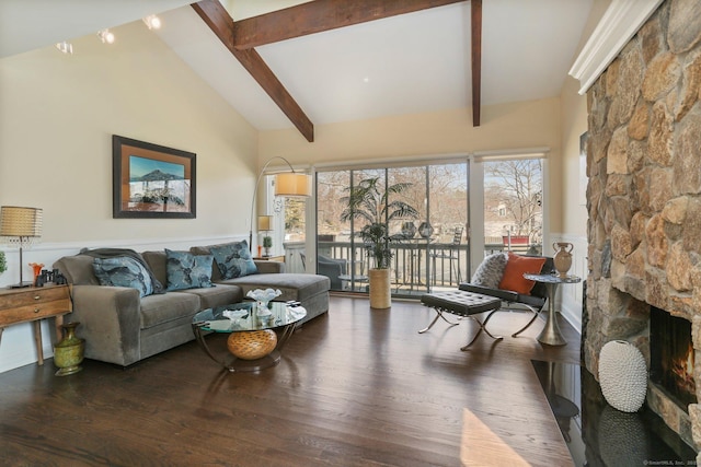 living area featuring a wainscoted wall, wood finished floors, a stone fireplace, high vaulted ceiling, and beam ceiling