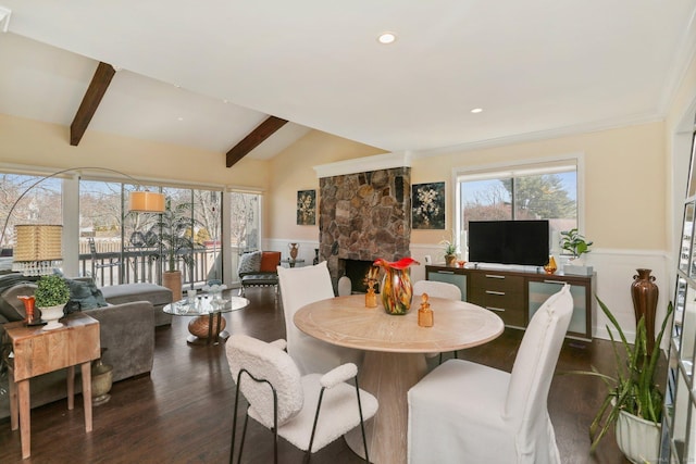 dining room with lofted ceiling with beams, a fireplace, a wealth of natural light, and wainscoting