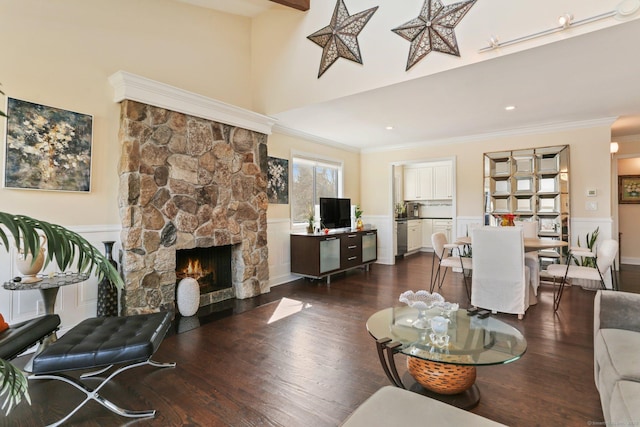 living area featuring crown molding, a fireplace, a high ceiling, and dark wood-type flooring