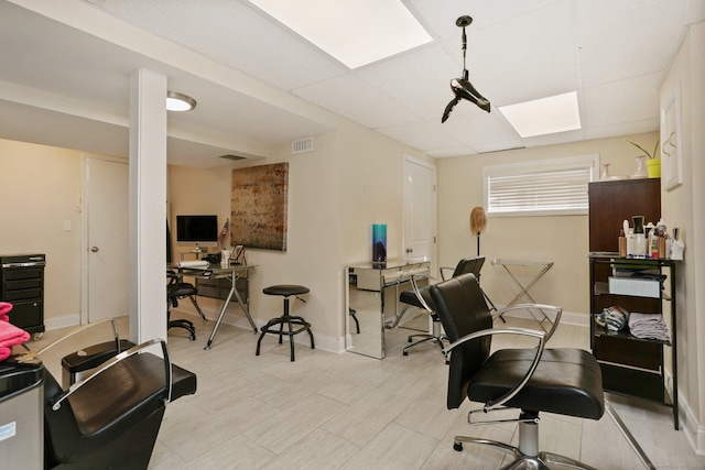 office with light wood finished floors, a drop ceiling, visible vents, and baseboards