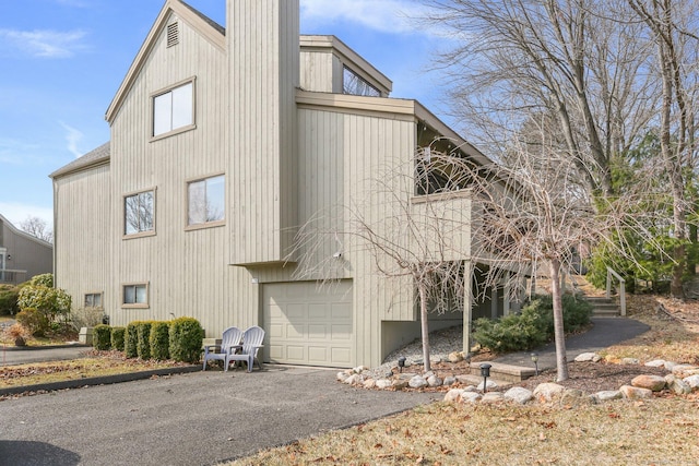 view of property exterior featuring an attached garage and a chimney