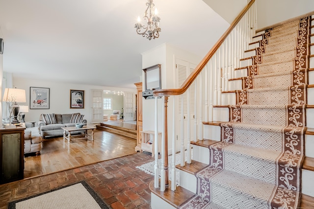 stairs featuring brick floor and an inviting chandelier