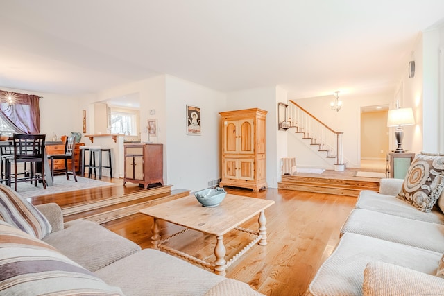 living area featuring a chandelier, wood finished floors, and stairs