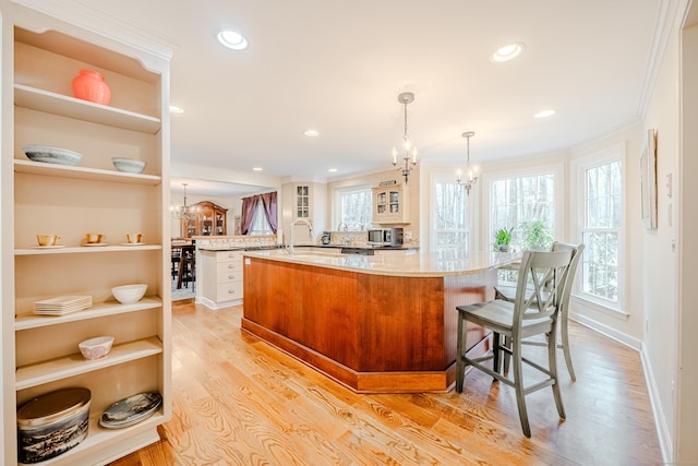 kitchen with glass insert cabinets, light wood-type flooring, open shelves, a notable chandelier, and recessed lighting