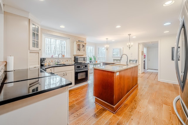 kitchen featuring light wood-style floors, crown molding, appliances with stainless steel finishes, and a sink