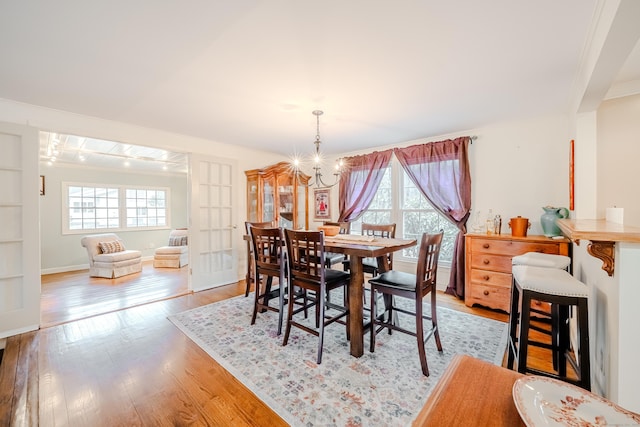 dining room with crown molding, plenty of natural light, light wood-style flooring, and an inviting chandelier