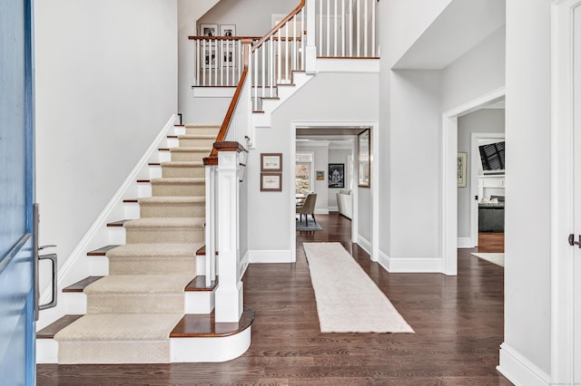 foyer with a towering ceiling, stairs, baseboards, and dark wood finished floors