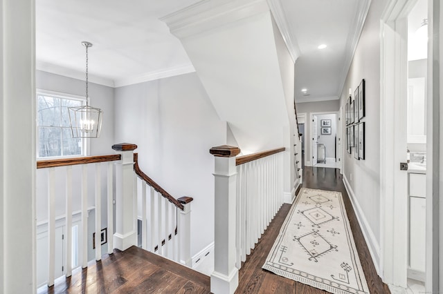 hall with baseboards, dark wood-type flooring, crown molding, an upstairs landing, and a chandelier