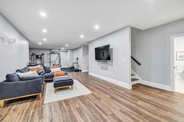 living room featuring stairs, baseboards, wood finished floors, and recessed lighting