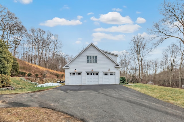 view of side of home with a garage, aphalt driveway, and a lawn