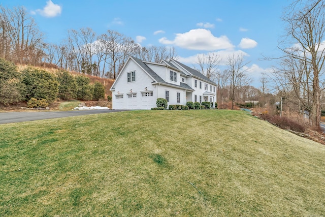 view of property exterior with an attached garage, aphalt driveway, and a lawn